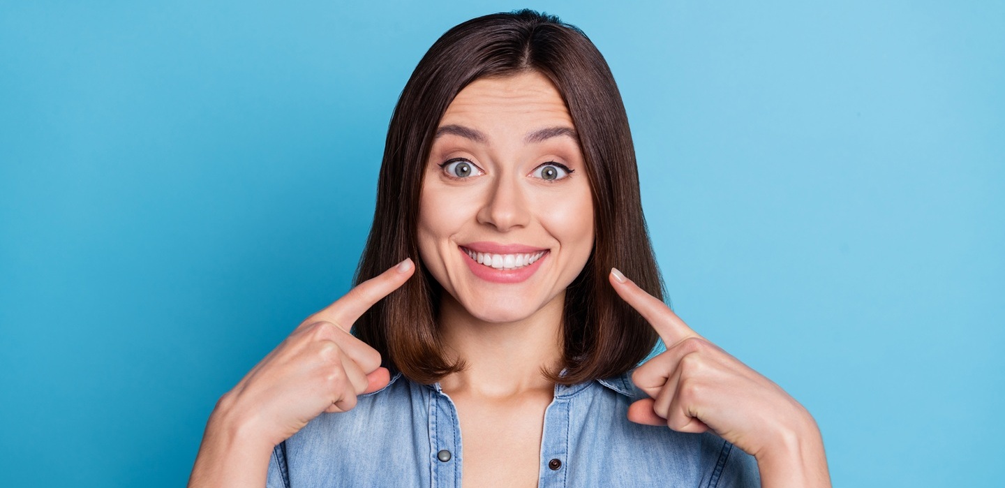 Photo of pretty adorable lady dressed denim shirt pointing fingers white teeth isolated blue color background Teeth-Whitening-Instructions-Elmhurst-IL